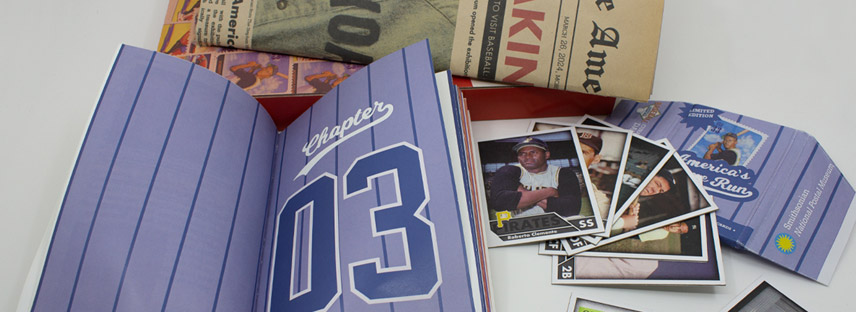 A spread of a baseball striped book, player cards, and folded newspaper