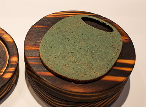 Bottom of a wooden coaster with a green cork olive